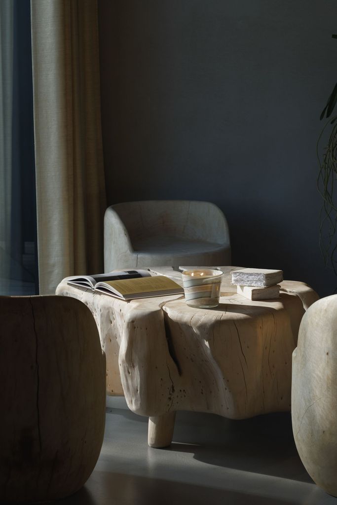 Peaceful and minimalist lounge space featuring candles, books and a light wooden table.