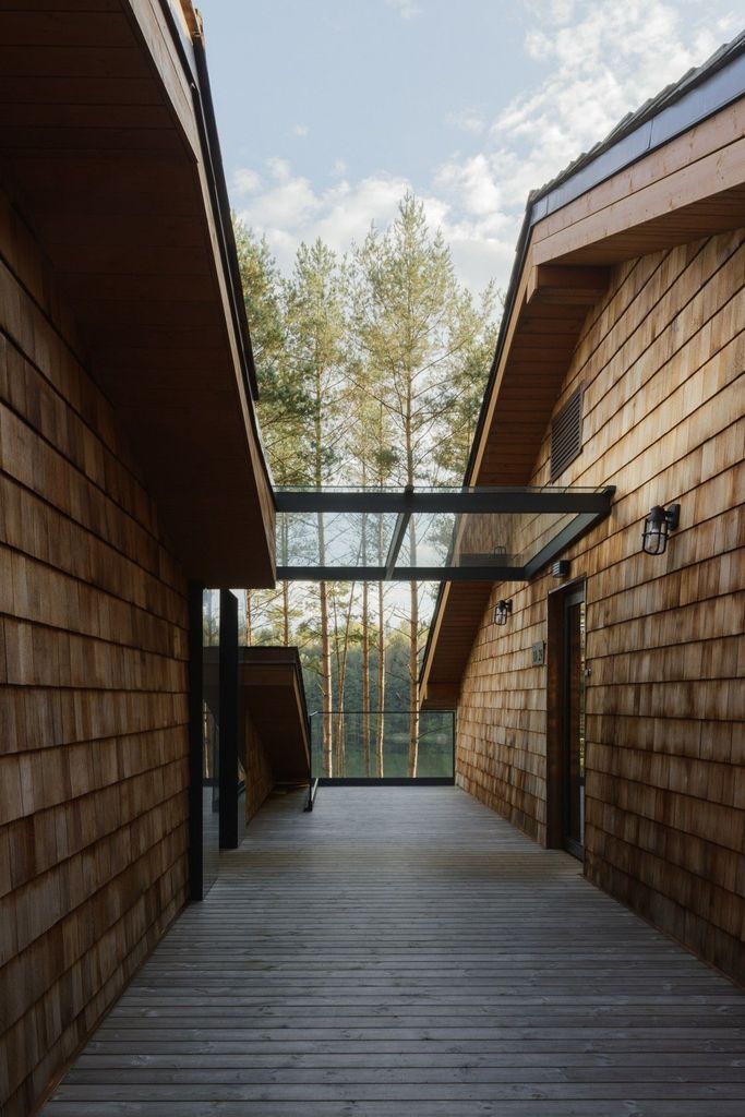 Wood-paneled walkway with glass roof at Esperanza Lake Resort surrounded by trees and lake.