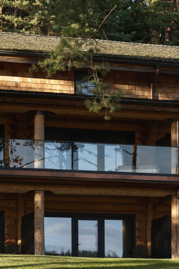 Wooden lodge balcony with glass railing at Esperanza Lake Resort offering serene forest scenery